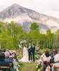 A soon-to-be husband and wife exchanging vows at their wedding ceremony and a mountain in in the dis